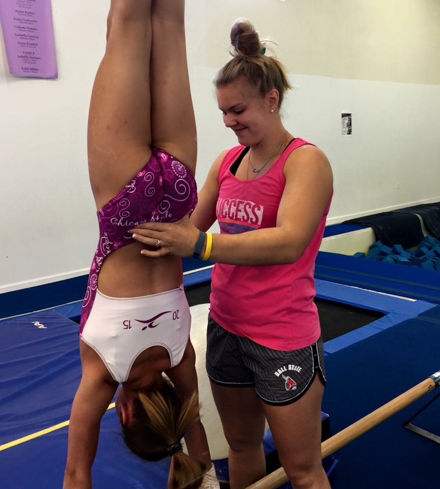 coach helping girl do handstand
